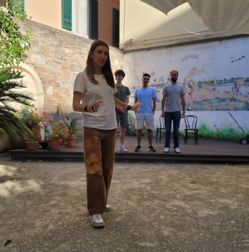 Facilitadora dirigiendo una sesión de teatro de improvisación al aire libre en Pisa